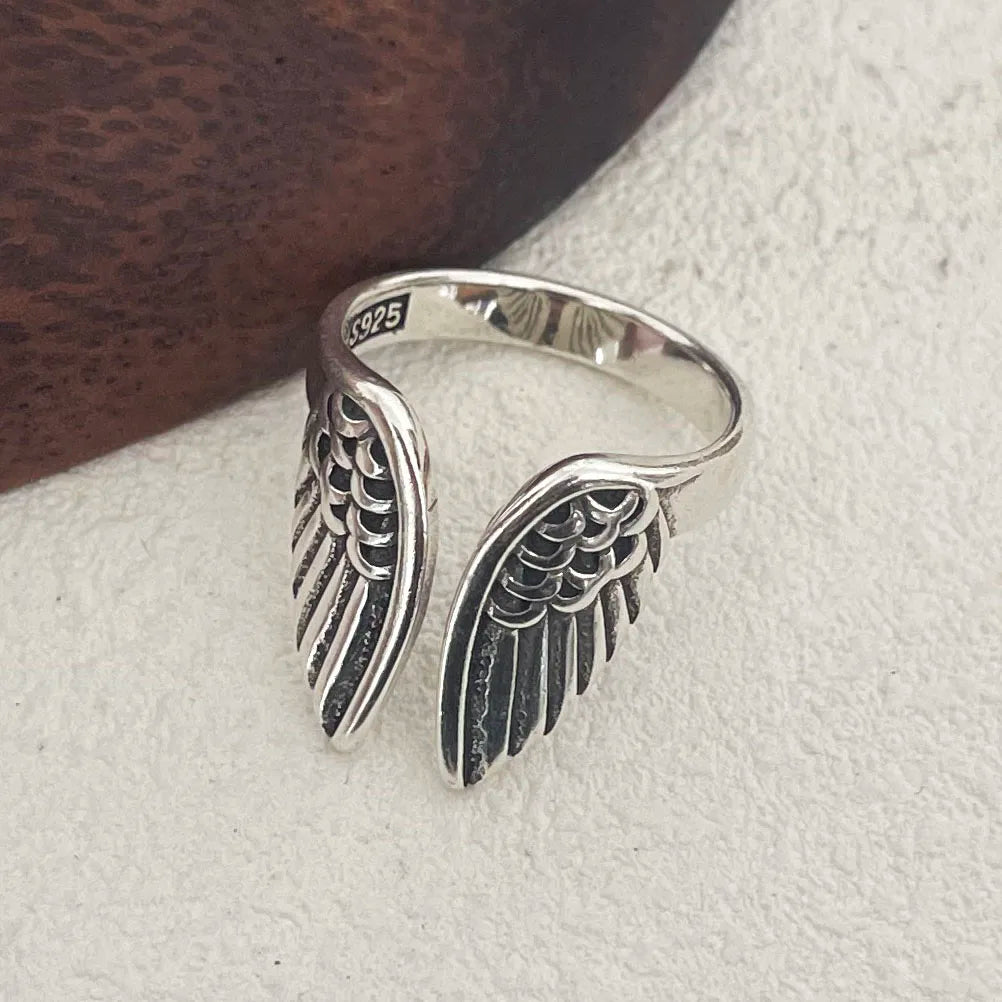 Angel wing sterling silver ring resting on book aesthetic jewelry