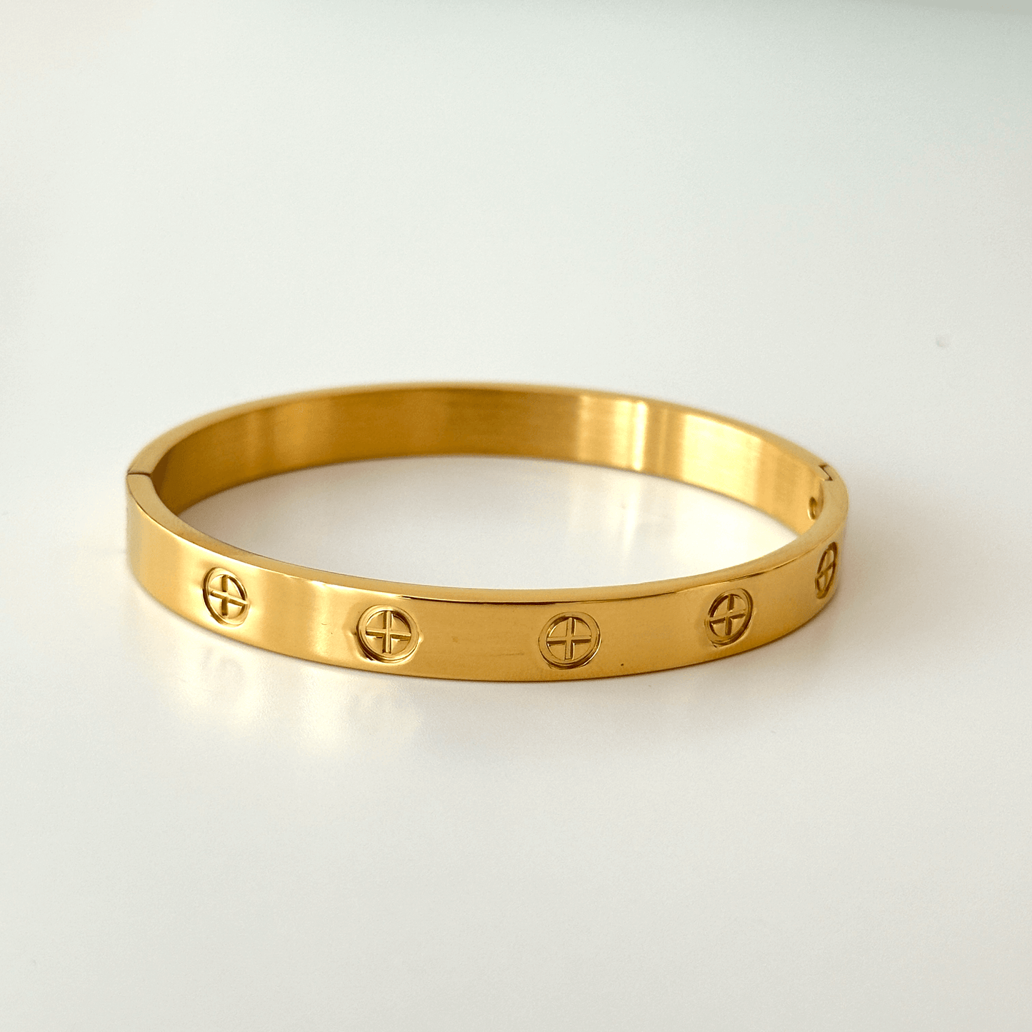 Gold bracelet with engraved symbols on a white background